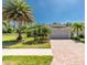 Charming home featuring a two-car garage, paver driveway, and tropical landscaping with palm trees at 4992 Brittain Way, North Port, FL 34287