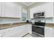 Bright kitchen featuring stainless steel appliances, white cabinets, granite countertops and tile flooring at 4992 Brittain Way, North Port, FL 34287