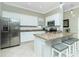 Bright kitchen with stainless steel refrigerator, granite countertops, white cabinetry, and island with bar seating at 4992 Brittain Way, North Port, FL 34287