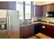 Efficient kitchen with stainless steel refrigerator and dark wood cabinets under a window at 4992 Brittain Way, North Port, FL 34287