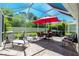 Spacious screened-in patio with dining and lounge areas, and a hot tub with an umbrella at 4992 Brittain Way, North Port, FL 34287