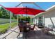 Covered brick patio featuring a red umbrella, outdoor furniture, and view of the yard at 4992 Brittain Way, North Port, FL 34287