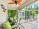 Enclosed patio featuring green seating, a ceiling fan, and a view of the surrounding greenery at 4992 Brittain Way, North Port, FL 34287