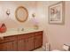 Bathroom vanity featuring a wood cabinet, and a stylish round mirror, enhanced by wall sconces and decor at 5181 Sandy Shore Ave, Sarasota, FL 34242