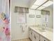 A cozy bathroom with a decorative floral curtain, a window, and a vanity with ample countertop space at 5181 Sandy Shore Ave, Sarasota, FL 34242