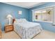 Bright blue bedroom with queen bed, side table, lamp, and large window for natural light at 5181 Sandy Shore Ave, Sarasota, FL 34242