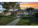 Charming single-story home boasts a manicured lawn, walkway, mature trees, and covered porch seating during sunset at 526 Allen St, Punta Gorda, FL 33950