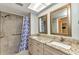 Bathroom features a granite countertop with double sinks and a shower with blue patterned shower curtain at 80 Hibiscus Dr, Punta Gorda, FL 33950