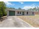 Charming single-story home featuring a green garage door and front door, set against a lush treed background at 105 Biscayne Dr, Port Charlotte, FL 33953
