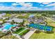 Aerial view of a community with a pond, tennis courts, clubhouse, and dog park in a beautifully landscaped setting at 1132 Moss Cove Ct, Port Charlotte, FL 33953
