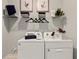 Functional laundry room with white appliances, storage shelves, and stylish decor at 1132 Moss Cove Ct, Port Charlotte, FL 33953