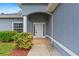 Close-up of the front entrance featuring a white door, brick landing, and manicured landscaping at 1275 Huntington St, North Port, FL 34288