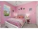 Bright pink bedroom featuring a white bed frame, colorful bedding and a window with blind at 1313 Wise Dr, North Port, FL 34286