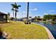 Scenic backyard with lush lawn, palm trees, and waterfront access to a canal at 148 Peckham St Se, Port Charlotte, FL 33952