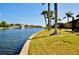 Waterfront property featuring well-maintained lawn, palm trees, and a serene canal view at 148 Peckham St Se, Port Charlotte, FL 33952