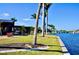 Waterfront backyard with manicured grass, tropical landscaping, and screened-in patio area at 148 Peckham St Se, Port Charlotte, FL 33952