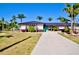 Single story home with well-manicured front lawn, palm trees, and a concrete driveway at 148 Peckham St Se, Port Charlotte, FL 33952