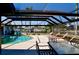 A covered outdoor living space featuring a sparkling pool and lounge chairs overlooking the canal at 148 Peckham St Se, Port Charlotte, FL 33952