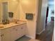 Bathroom with double sinks, white cabinets, and access to the hallway at 1488 Squaw Ln, North Port, FL 34286