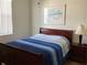Bedroom with a wooden bed frame and a blue-striped bedspread, enhanced by natural light at 1488 Squaw Ln, North Port, FL 34286