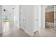 Bright hallway with neutral tile flooring leading to a well-lit bathroom and other rooms at 16029 Mulrion Blvd, Punta Gorda, FL 33982