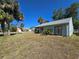 An angle view of backyard featuring sliding glass doors, partial view of a screened porch, and tropical landscaping at 19583 Kapok Ct, Port Charlotte, FL 33952