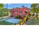Charming coral home featuring a brick driveway, tile roof accents, and lush tropical landscaping at 2002 Central Ave, Sarasota, FL 34234