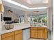 Open kitchen with wood cabinets, lots of windows, and view to living room and outdoor pool at 2288 Prague Ln, Punta Gorda, FL 33983