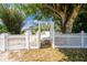 Charming front yard with a white picket fence and mature trees creating a tranquil, shaded curb appeal at 31037 Prairie Creek Dr, Punta Gorda, FL 33982