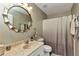 Well-lit bathroom features a large mirror, neutral colors, and a shower with a decorative curtain at 3104 Garbett Ter, North Port, FL 34288