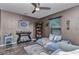 Cozy bedroom featuring a sitting area, accent wall, ceiling fan, and shelving for collectibles at 3104 Garbett Ter, North Port, FL 34288