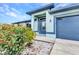 Close up of a charming front entrance with blue trim, a garage, a well maintained yard and landscaping at 3104 Garbett Ter, North Port, FL 34288