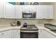 Well-appointed kitchen with white cabinets, stainless steel microwave and oven range at 3104 Garbett Ter, North Port, FL 34288