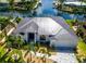 Aerial view of a waterfront home with a metal roof, lush landscaping, and boat dock access to a canal at 3520 Caya Largo Ct, Punta Gorda, FL 33950