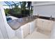 Outdoor kitchen featuring a granite countertop, grill, sink and storage with a pool view at 3787 Whippoorwill Ct, Punta Gorda, FL 33950