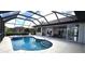 Backyard pool featuring a screened-in enclosure, outdoor kitchen, patio dining area, and lush landscaping at 3787 Whippoorwill Ct, Punta Gorda, FL 33950