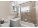Bathroom with gray vanity, mirror, tiled walls, bathtub, shower, and window at 6309 Pontiac Ln, North Port, FL 34287