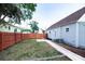 Spacious backyard with a grassy area, a concrete path and a red stained fence at 7413 S Elliott St, Tampa, FL 33616