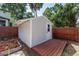 Charming backyard shed with a wooden deck and a red stained fence at 7413 S Elliott St, Tampa, FL 33616