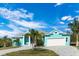Charming, light blue single-story home with a well-manicured lawn, two-car garage, and tropical landscaping at 8084 Burwell Cir, Port Charlotte, FL 33981