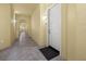 Neutral hallway with yellow walls, leading to apartment door with dark mat on tile floor at 95 Vivante Blvd # 9524, Punta Gorda, FL 33950