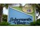 Colorful sign for Fisherman's Village with palm trees and tropical foliage at 14061 Heritage Landing Blvd # 445, Punta Gorda, FL 33955