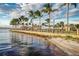 Waterfront promenade with palm trees, a beach, and the bridge beyond the seating area at 14061 Heritage Landing Blvd # 445, Punta Gorda, FL 33955