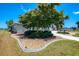 Lush lawn with a mature tree, manicured landscaping, and a curved walkway create inviting curb appeal at 142 Rotonda Cir, Rotonda West, FL 33947