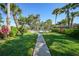 Inviting walkway leading to a shuffleboard court surrounded by tropical landscaping and benches for relaxation at 1515 Forrest Nelson Blvd # N101, Port Charlotte, FL 33952