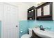 Bathroom with blue tile has a sink, toilet, built-in soap dish and black overhead storage at 159 Godfrey Ne Ave, Port Charlotte, FL 33952