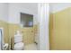 Bathroom with yellow retro tile shower and flooring features a white toilet and small window at 159 Godfrey Ne Ave, Port Charlotte, FL 33952