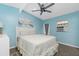 Light blue bedroom features a queen bed, ceiling fan, and view of the fenced yard at 159 Godfrey Ne Ave, Port Charlotte, FL 33952