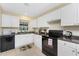 Well-lit kitchen featuring white cabinets, black appliances, and tiled floor at 159 Godfrey Ne Ave, Port Charlotte, FL 33952