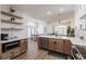 Open-concept kitchen with stainless steel appliances, floating shelves, and seamless flow to the living area at 1711 Boca Raton Ct, Punta Gorda, FL 33950